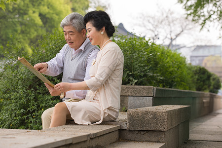 老年夫妻坐在石椅上看地图高清图片