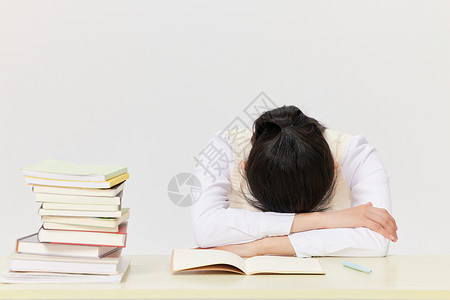 冲刺期末疲惫的学生趴在课桌前休息背景