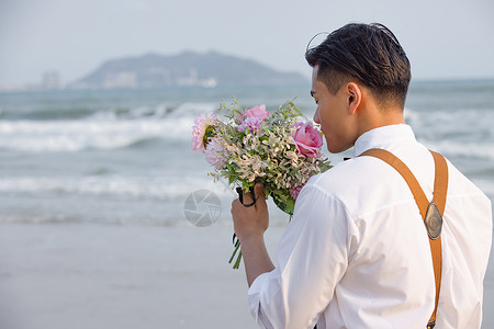 海边西装男性拿着手捧花看海背景