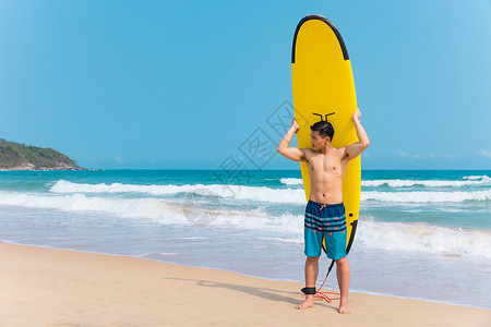 海边沙滩裤青年男性拿冲浪板背景图片