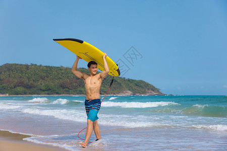 冲浪男生海边沙滩裤青年男性头顶冲浪板背景