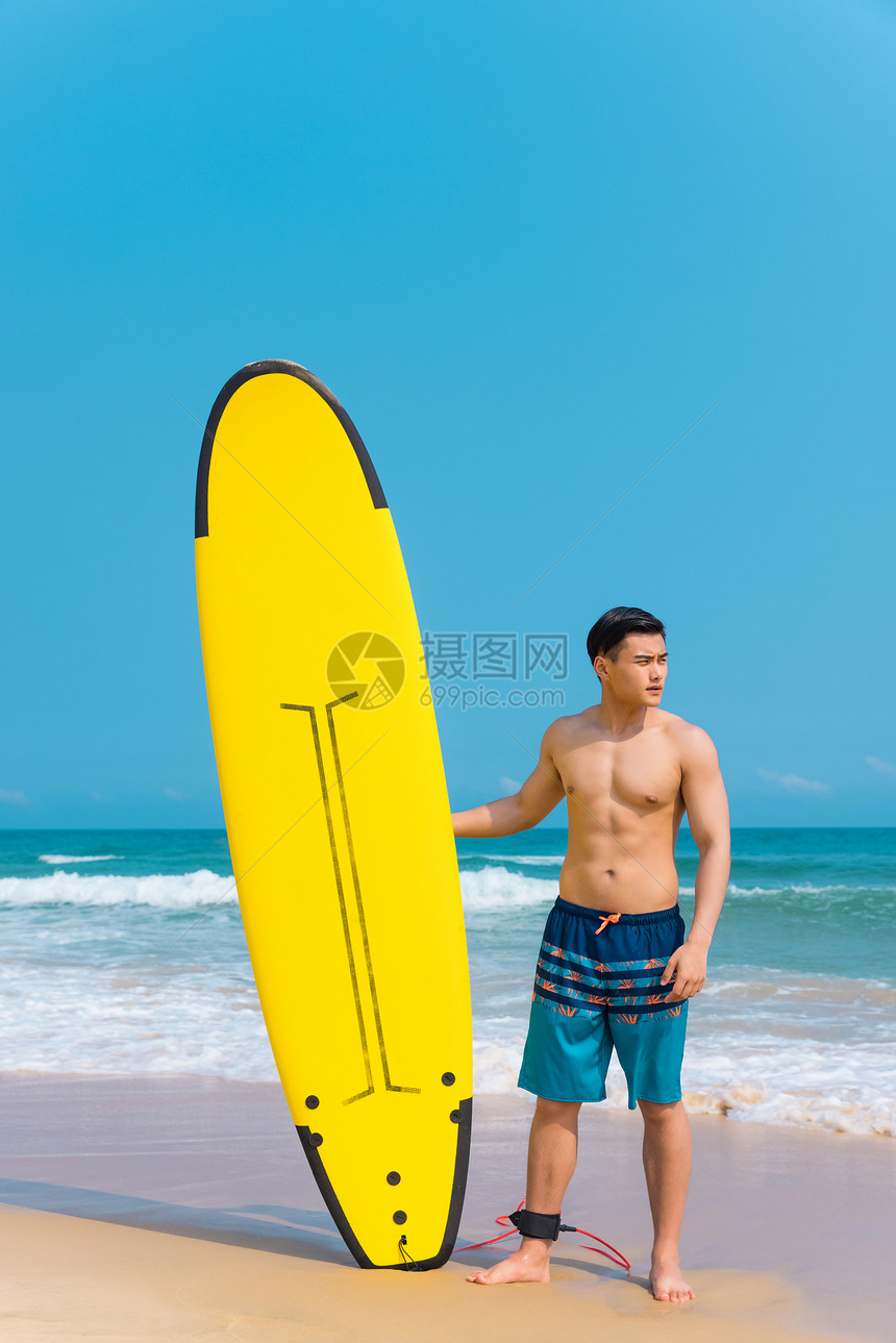 海边沙滩裤青年男性拿冲浪板图片