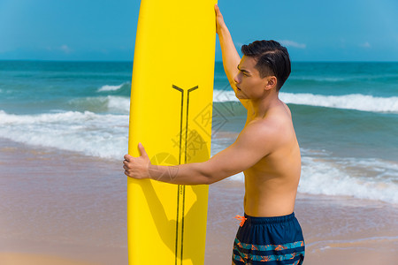 海边沙滩裤青年男性拿冲浪板背景图片