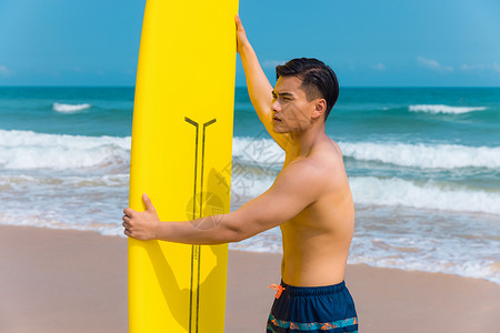 海边沙滩裤青年男性拿冲浪板背景图片