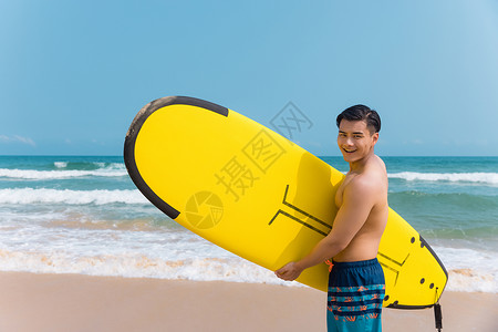 海边沙滩裤青年男性拿冲浪板背景图片