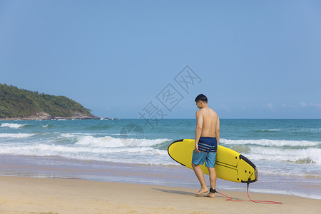 海边沙滩裤青年男性拿冲浪板背景图片