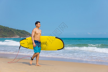 海边沙滩裤青年男性拿冲浪板背景图片