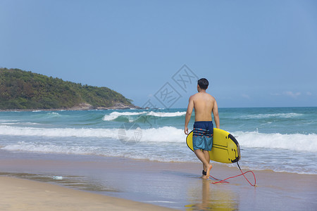 海边沙滩裤青年男性拿冲浪板背影高清图片