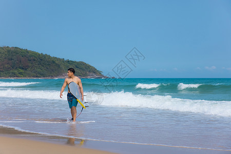 海边沙滩裤青年男性拿冲浪板背景图片