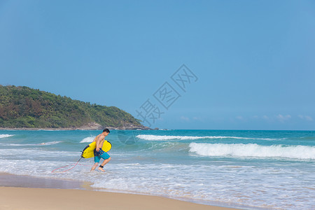 海边沙滩裤青年男性拿冲浪板走向大海背景图片