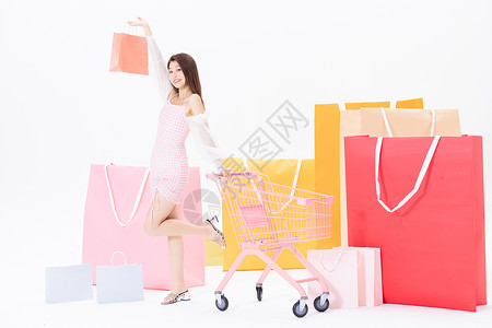 女性推着购物车举着购物袋图片