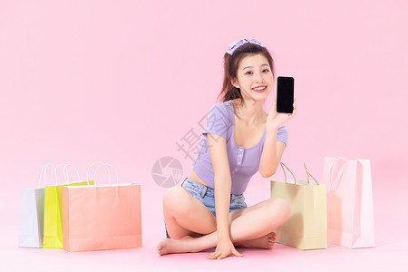坐在购物袋旁的美女展示手机图片