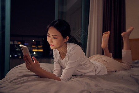 睡前看手机青年女性深夜睡前躺床上玩手机背景