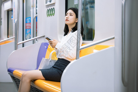 地铁上看手机的女性图片