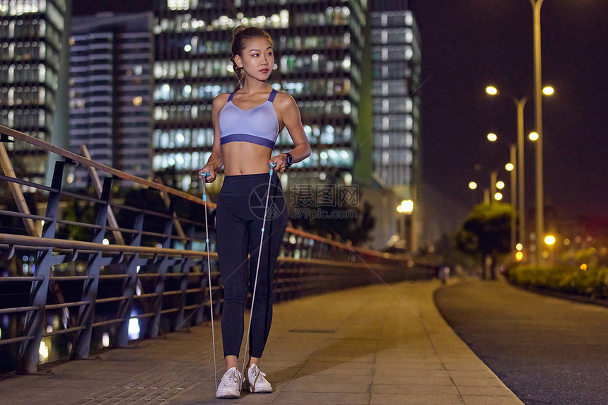 城市户外夜景健身美女跳绳图片