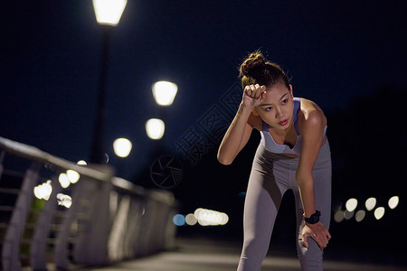 城市户外夜跑美女擦汗图片