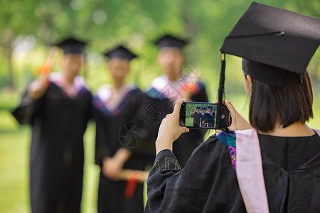 女生用手机给同学们拍毕业照背景图片