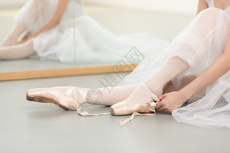 开阔的舞蹈教室芭蕾舞者绑舞鞋特写背景