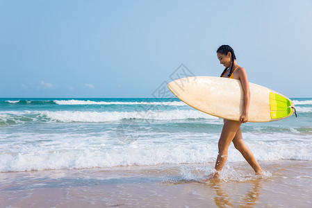 夏日海边比基尼美女抱着冲浪板行走图片