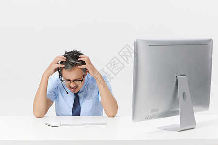 在电脑上前工作的中年男客服表情苦恼高清图片