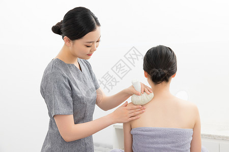 颈椎变形按摩师给顾客做肩部spa艾草理疗背景