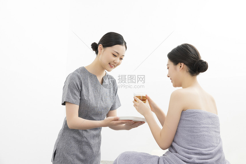 美容院按摩师为美女顾客提供茶水图片