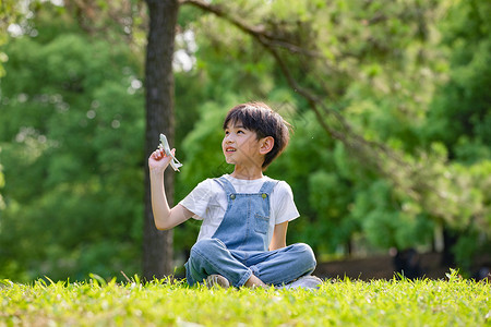 户外手拿玩具飞机的小男孩高清图片