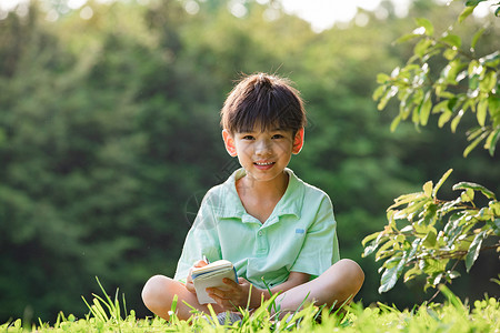 儿童节观察蚂蚁坐在草地上写观察日记的小男孩背景