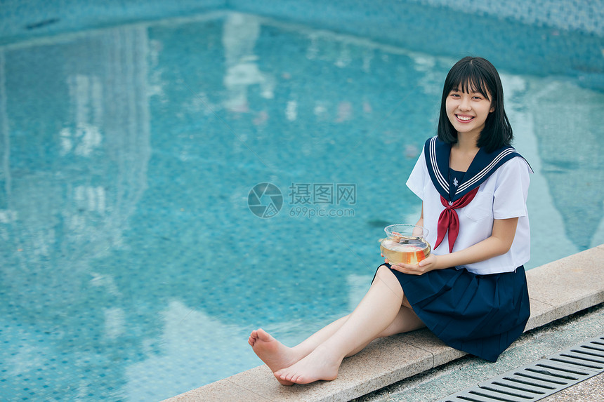 日系美女抱着鱼缸坐在泳池边图片