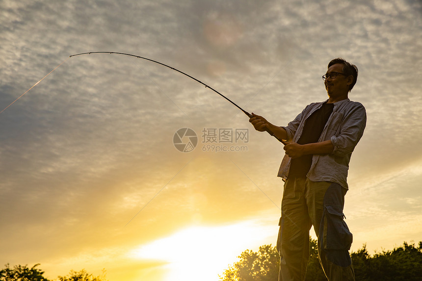 夕阳时分钓鱼的男性图片