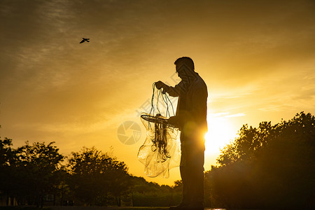 夕阳下整理渔具的中年人高清图片