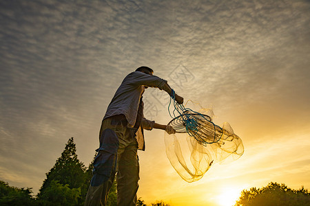 夕阳下撒网的渔民背景图片