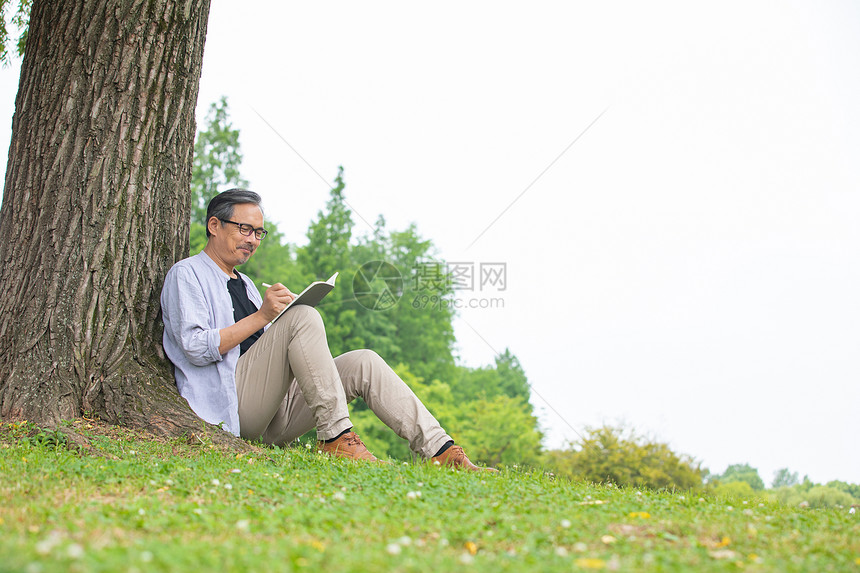 男性坐在大树下记录图片