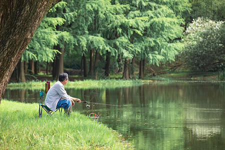 钓飞鱼在湖边悠闲钓鱼的男性背景