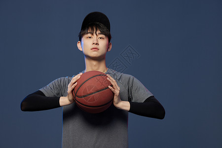 潮男模特男青年手拿篮球背景