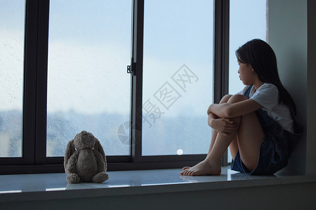 孤单的小女孩看着窗外高清图片