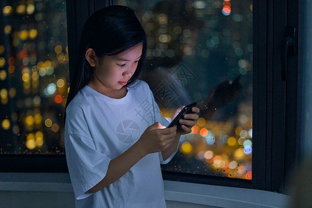 夜晚在家使用手机的小女孩图片