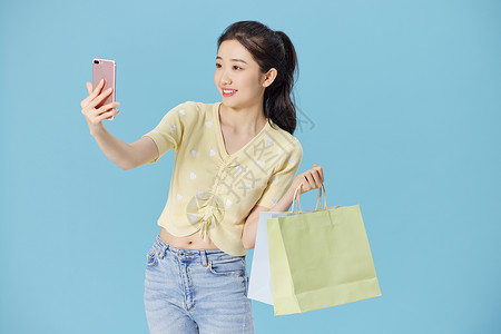 购物女性拿着手机自拍图片