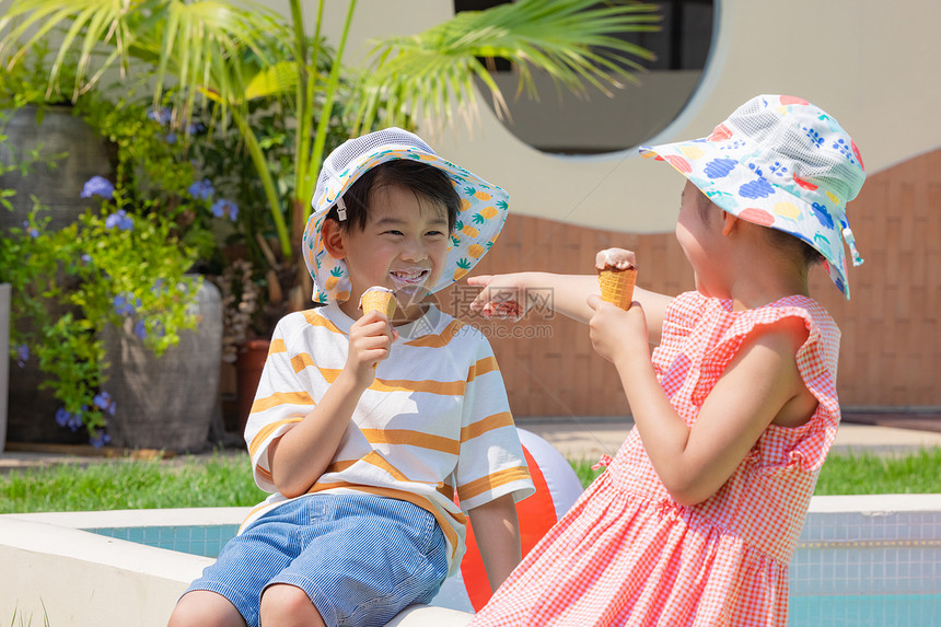 小男孩小女孩手拿冰淇淋坐在泳池边玩耍图片