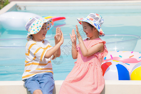 小男孩和小女孩坐在泳池边玩游戏图片
