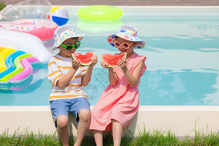 小男孩和小女孩坐在泳池旁开心吃西瓜图片