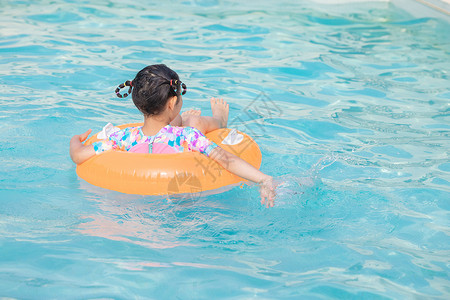 小女孩躺在游泳圈上游泳背影背景