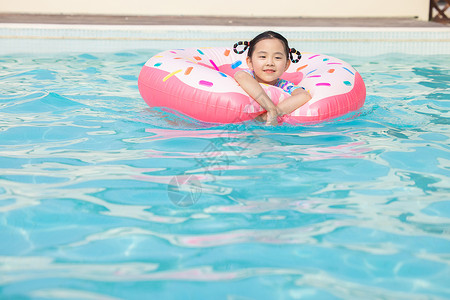 小女孩趴在游泳圈上开心戏水背景图片