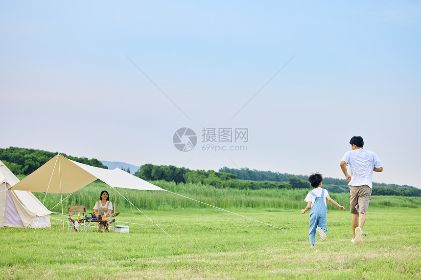 小男孩和爸爸在草坪上追逐打闹背影图片