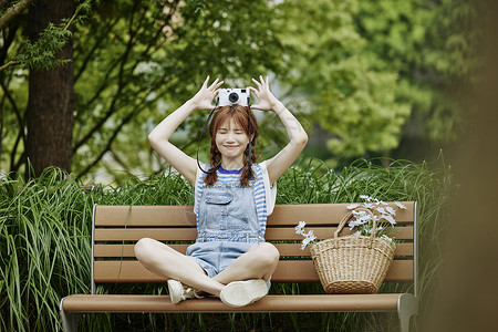 坐在长椅上拍照的夏日美女背景图片
