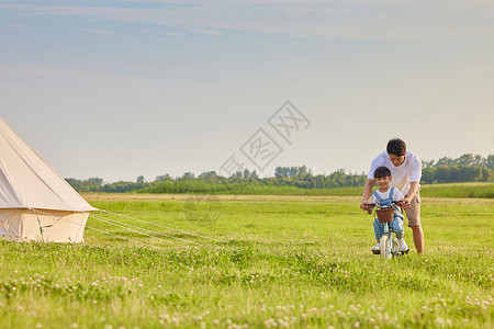 学自行车年轻爸爸陪伴小男孩学骑自行车背景