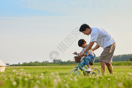 骑车郊游的孩子年轻爸爸陪伴小男孩学骑自行车背景