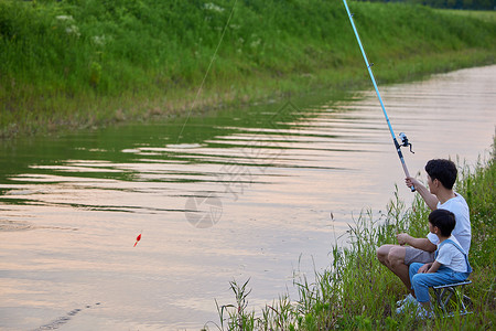周末钓鱼年轻爸爸带着儿子户外钓鱼背景