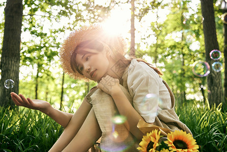 吹泡泡太阳坐在草地前吹泡泡的清新夏日美女背景