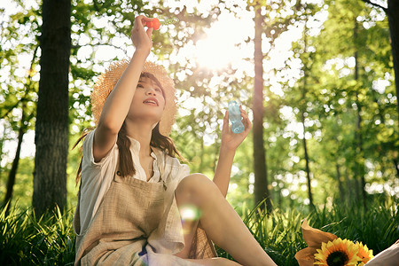 吹泡泡太阳坐在草地前吹泡泡的清新夏日美女背景